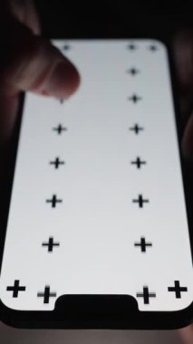 Dikey video. Beyaz ekranlı akıllı bir telefonun yakın plan görüntüsü ve karanlıkta tuvalette oturan bir adam tarafından kaydırılan izleme izleri..