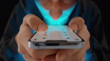 Beyaz Ekran Düzeni ve İzleme İşaretleri olan akıllı telefon. Kapüşonlu Adam, Ekrandaki Mavi Işık tarafından aydınlatılmış, Görüntüleriniz Arasında Kaydedilmiş.