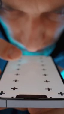 Dikey video. Kapüşonlu Genç Adam 'ın Beyaz Ekran ve Ekrandaki Hareketleri İzleyen Akıllı Telefonla Yakın Çekimi. Chroma Anahtarı Model.