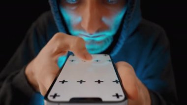 Akıllı telefon ekranından gelen mavi ışık, kapüşonlu genç adamın yüzünü aydınlatırken parmaklarıyla sayfaları karıştırıyor. Chroma Anahtarı Model.