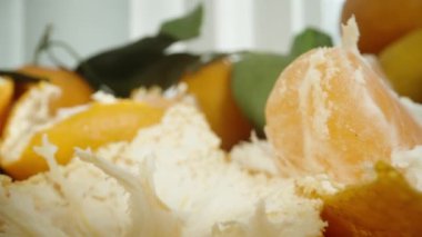 Kamera masadaki mandalina kabuklarından süzülüyor, segmentleri soyuyor ve yakınlarda ayrılıyor. Dolly kaydırıcı aşırı yakın çekim.