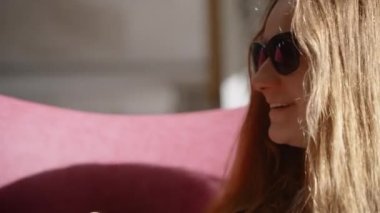 Güneş gözlüklü genç bir kadın Beyaz Kupa 'dan kahve içiyor ve gülümsüyor.