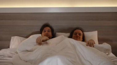 Bir çift, bir erkek ve bir kadın, örtülerin altından çıkıyor, molada şampanyalarını yudumluyor, ve sonra kendilerini tekrar örtünün altına saklıyorlar..