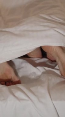 Dikey video. Yatakta bir erkek ve bir kadının bacaklarının görüntüsü, üstte bir adam, ama çabucak bitiriyor, iniyor ve uykuya dalıyor