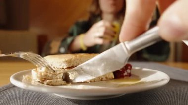 Bir parça krep kesmek ve üzerine bal sürmek, kiraz çileğiyle birlikte. Yakın plan, restoranda kahvaltı..