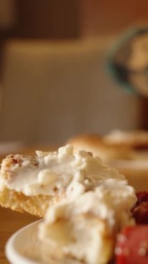 Dikey video. Bir kadınla bir restoranda kahvaltı. Krem peynirle ve tabakta yumurtalı domatesle kaplanmış rulo. Yakın plan..