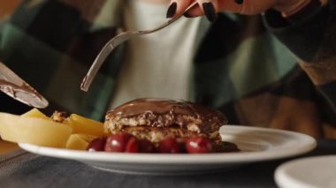 Lokantada bir kadın üzerine çikolata konmuş, kiraz ve şeftali süslemeli krep yiyor. Yakın plan..