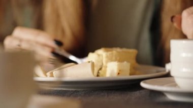 Bir kadın jambonlu omletle kahvaltı yapıyor. Çatalla parçalara ayırıyor. Yakın plan..