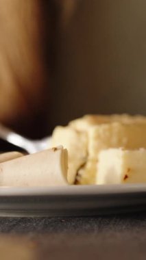 Dikey video. Bir kadın jambonlu omletle kahvaltı yapıyor. Çatalla parçalara ayırıyor. Yakın plan..