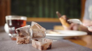 Tek porsiyon çikolata paketleri açtığında, bir adam restorandaki bir masada krep yiyor. Sıcak çay yakında..