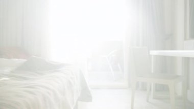 Beyaz Yataktaki Genç Bir Kadın, Yeni Uyandı, Uzaktan kumandayla hemen TV 'yi açıyor. Sabah güneşinin ışıltılı ışınları Yatak odasına nüfuz ediyor.