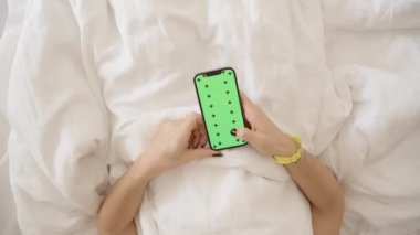 Bir otelde yemek ya da oda temizliği sipariş etme kavramı. Yeşil Ekran Modeli ve Yatakta Yatarken İzleme İşaretleri ile Akıllı Telefondan Kadın Elleri Kaydırıyor. Üst Görünüm.