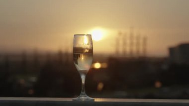Alçak Güneş Şampanya bardağına yansıyor, Gemiler Uzakta.