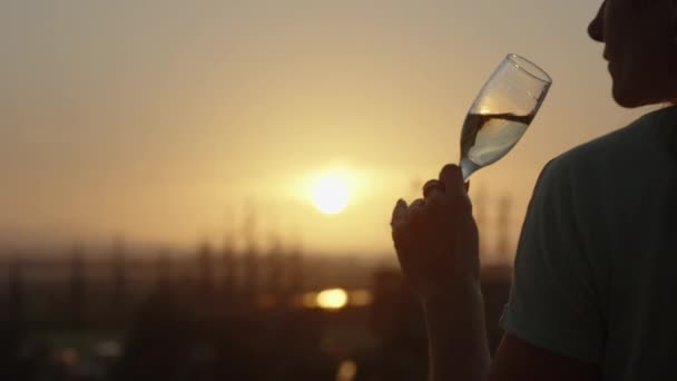 年轻女子站在阳台上 一边喝香槟 一边欣赏夕阳西下的船尾 — 图库视频影像