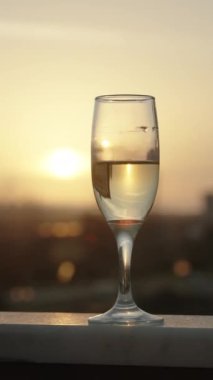 Günbatımında Güneş 'i yansıtan bir şampanya kadehinin dikey videosu.