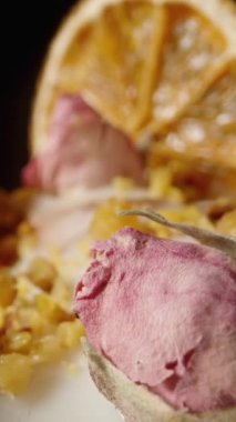 Dikey video. Kurutulmuş portakal dilimleri ve gül çiçekleriyle süslenmiş siyah arkaplanda yumurtalı Paskalya keki. Dolly kaydırıcı aşırı yakın çekim.