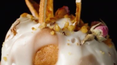 Çiçekler ve portakalla süslenmiş, siyah arka planda beyaz kremalı bir Paskalya pastası. Dolly kaydırıcı aşırı yakın çekim.