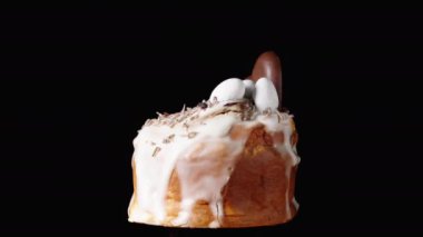 Siyah arka planda, beyaz kremalı bir pasta, bir çikolatalı kalp ve üzerinde küçük yumurtalar dönüyor. Paskalya Kutlaması.