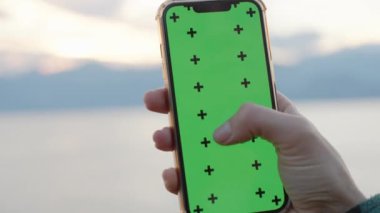 Yeşil Ekran ve İzleme İşaretleyicili Akıllı Telefona Odaklanma Efekti. Deniz kıyısındaki yüksek uçurumdaki kadın. Ekleme için Yerleşim.