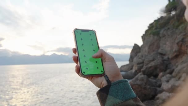 Kvinna Håller Telefon Och Rullar Genom Grön Skärm Med Spårmarkörer — Stockvideo