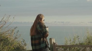 Yüksek bir uçurumdan gün batımında, bir kadın güzel bir manzara yerine telefonuna bakar..