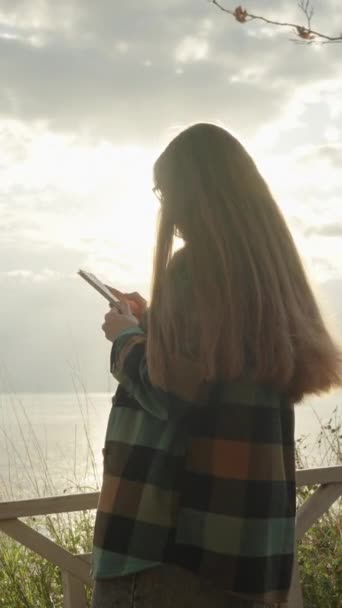 Άνεμος Χαϊδεύει Μαλλιά Και Πουκάμισο Μιας Γυναίκας Που Κοιτάζει Τηλέφωνό — Αρχείο Βίντεο