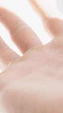 Dikey video. Gölge 'den çıkan bir adamın eli güneş ışınlarına dokunuyor. Beyaz ve Parlak Arkaplanda.