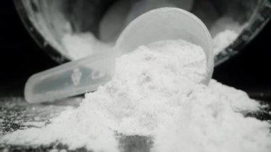 Siyah Arkaplan 'da, Beyaz Toz, Ölçme Kaşığından serpilmiştir. Arka plandaki kavanoz. Dolly kaydırıcı, kapat..