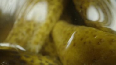 Kavanozdan salatalık turşusuna uzanan bir adamın yakın çekimi. Üst görünüm, makro kaydırıcı.