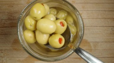 Bir kaşık kullanarak kavanozdan biberli bir avuç tuzlanmış zeytin alıp geri atıyorum. Üst görünüm, yavaş çekim.