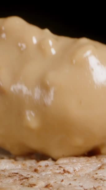 Вертикальное Видео Черном Фоне Распространяя Арахисовое Масло Ножом Рисовый Торт — стоковое видео