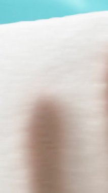 Dikey video. Mavi arka planda bir peçeteyle bardağı silerim. Ters taraftan bak, yakın plan..