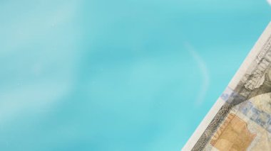 Mavi arka planda, 100 dolarlık banknotları masaya serptim. Düşük açı görünümü pencereye odaklan