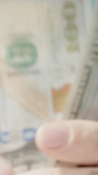 垂直录像 一个人把一百元钞票放在一张透明的桌子上 蓝色的背景衬托下 盖满了整个空间 — 图库视频影像