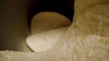 Mısır cipsleri, hiperbolik paraboloit şeklinde, siyah arka plana karşı konserve kutusundan masaya saçılmış. Dolly kaydırıcı, kapat..