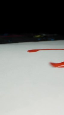 Dikey video. Sanatçı, beyaz bir tuvale kırmızı boya ile bir kalp şekli çizer. Dolly kaydırıcı, kapat..