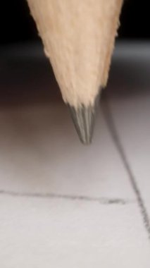 Dikey video. Bir el tarafından tutulan ve kağıda bir şeyler yazan bir kalemin yakın çekimi. POV.