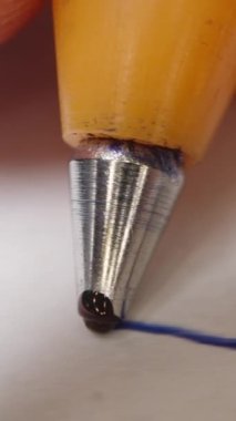 Dikey video. Elde tükenmez kalem, makro atış, sonunda topun içinden mürekkep akıyor. Bir şeyler yazıyor..