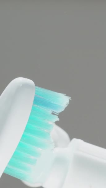 垂直录像 将牙膏挤压在牙刷上 并在特写中显示出来 蓝色的鬃毛 — 图库视频影像