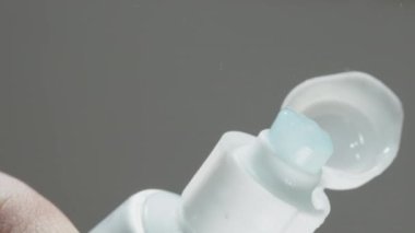 İçinde beyazlatıcı kareler olan mavi diş macunu, alttaki görünüm, makro. Tüpten çıkarıyorum..