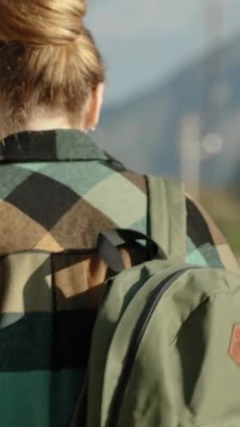 垂直录像 一个身穿绿色格子衬衫背着背包的年轻女子的背影 在高山和阳光灿烂的天气中独自旅行 — 图库视频影像