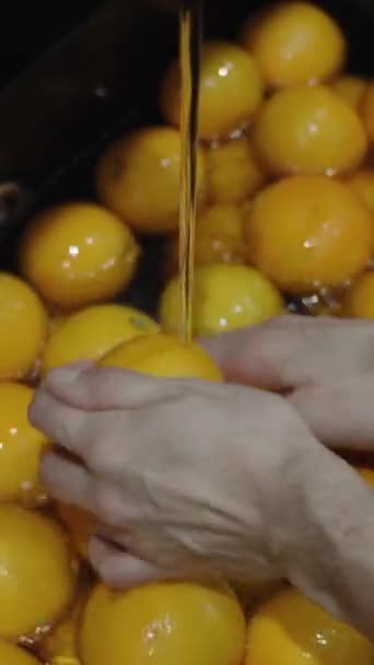 バーティカルビデオ 男によって洗浄されている水とオレンジで満たされた全体の黒いシンク — ストック動画