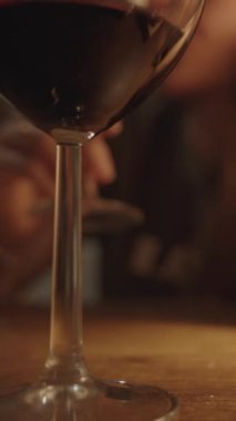 Masadaki iki kadeh kırmızı şarap, romantik bir randevu, arka planda içen bir kadın..