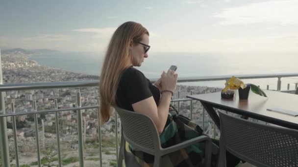 Dağın Tepesindeki Bir Kafede Deniz Şehir Manzaralı Genç Bir Kadın — Stok video