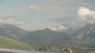 Yüksek bir dağdaki restoranda bir fincan kahve içelim. Şehir manzarası ve arka planda ağaçlarla kaplı dağlar olsun..