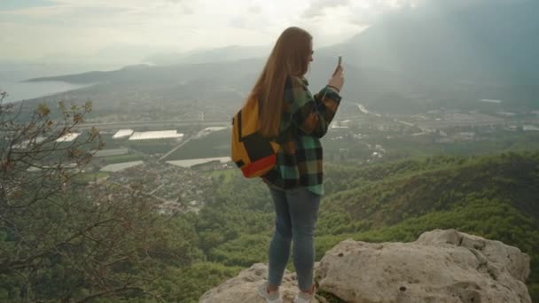 Kobieta Jasnym Plecakiem Koszulą Kratkę Rejestruje Widoki Góry Aparacie Telefonicznym — Wideo stockowe
