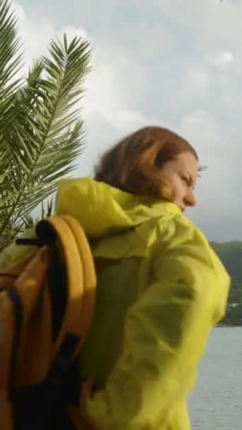 광선으로 날씨를 캐스트 노란색 비옷을 여자가 바다를 바라보기 가장자리에 — 비디오