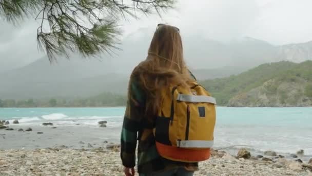 海の湾に沿って松林を巡って 寒い日を過ごす オレンジ色のバックパックが歩いている女性 — ストック動画
