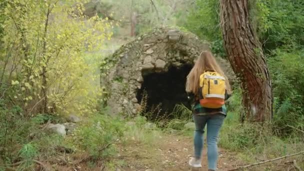 一个女人带着古老的建筑穿过森林 凝视着一个石坑 — 图库视频影像