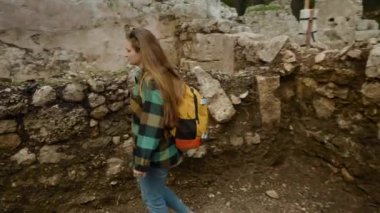 Phaselis 'in antik harabelerinde genç bir kadın yıkılmış bir binanın koridorlarında yürüyor..